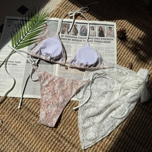 Detail of three-piece lace bikini with sheer pink mesh cover-up and metal buckle