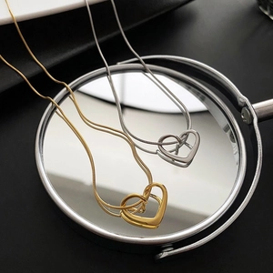 Elegant gold and silver hollow heart pendant necklaces on mirror with snake chain