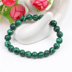 Detail of 8mm green tiger eye beads bracelet on hand display with floral accent