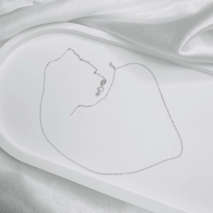 Detail of silver S925 cross chain with spring clasp and metal bead on white display tray