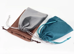 Dettaglio di tre sacchetti per gioielli in velluto con coulisse marrone, grigio e blu