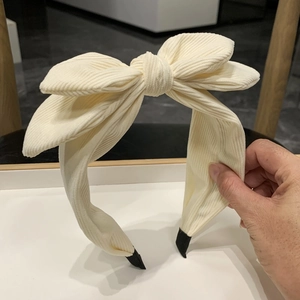 Detail of cream corduroy fabric and large bow on a high-top cute headband for women