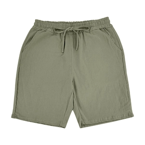 Detail of olive green linen shorts featuring an elastic waistband and matching drawstring