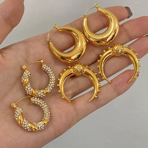 Set of gold stainless steel hoop earrings with crystal pavé held in hand for scale