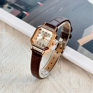 Elegant gold square watch with beige dial and brown leather strap on soft fabric