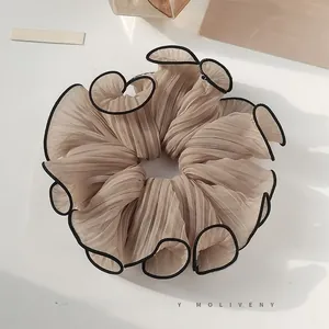 Detail of champagne pleated scrunchie with contrast black stitching on soft fabric