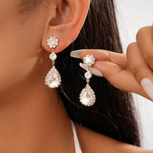 Detailed close-up of crystal pear-shaped drop earrings with floral accents on model