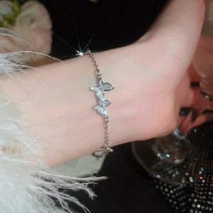 Detail of silver butterfly bracelet featuring sparkling zircon stones on a soft feather background