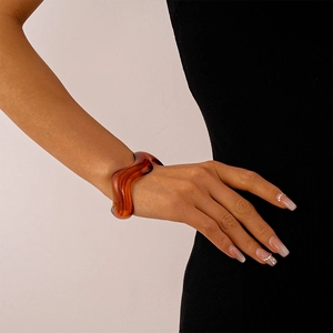 Close-up of wavy amber acrylic cuff bracelet on wrist with elegant resin texture