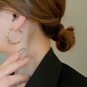 Close-up of silver irregular geometric hoop earrings with textured molten metal finish