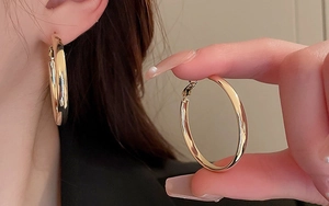 Close-up of chunky gold-plated stainless steel hoop earrings with polished finish