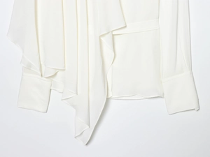 Detailed view of white long sleeve shirt showing silk drape texture and pleated cuffs