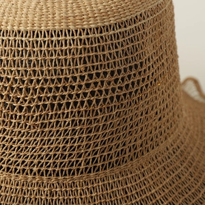 Macro shot of raffia sun hat texture featuring hollow patterns and woven gold threads