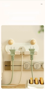 Detail of wall-mounted plug organizer with wooden hooks and three slots on cream wall