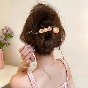 Detail of a resin duckbill hair clip with orange-pink beads and rhinestones on a model