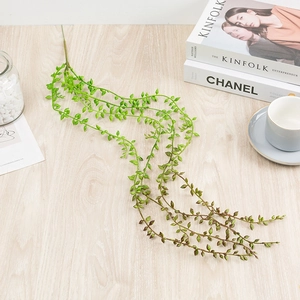 Artificial hanging succulent plant with realistic green beads on a minimalist wood surface