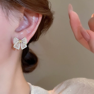 Macro shot of silver needle bow earrings with white pearls and sparkling diamonds
