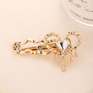 Detail of a gold heart hair clip with a melting metal texture and sparkling rhinestones