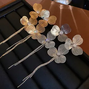 Boucles d'oreilles fleurs dorées et argentées à pompons avec zircons sur plateau noir