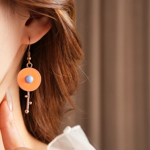 Detail of vintage round enamel drop earrings with key charm on model wearing