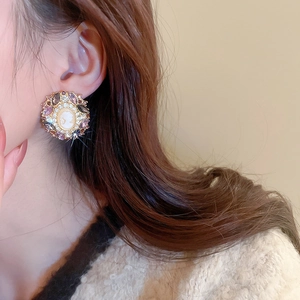 Close-up of vintage Baroque cameo earrings with purple gemstones on a model's ear