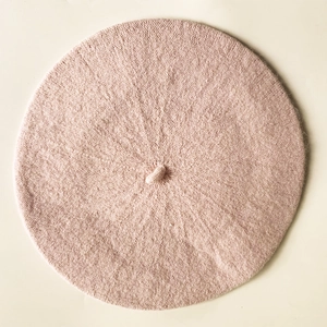 Close-up of pink knitted cashmere beret top showing fine yarn texture and small stem detail