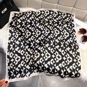 Elegant silk square scarf with black and white geometric patterns on a soft white rug