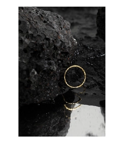 Nahaufnahme eines goldenen Rings mit Zinnfolien-Struktur auf schwarzem Vulkanstein