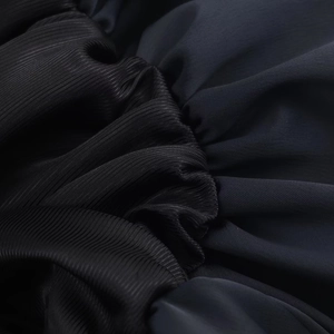 Gros plan détaillé sur la texture du tissu noir plissé de l'élégante mini robe ballon