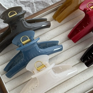 Five colored 11cm curved shark hair clips arranged in a textured beige gift box display