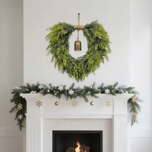 Heart-shaped Christmas wreath with vintage bell and cedar branches for mantel decor