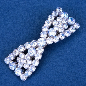 Sparkling crystal bow hair clip with silver finish on a premium textured navy background