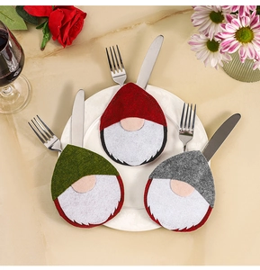 Close-up of festive gnome cutlery holders in red, green, and gray on a dinner table