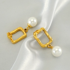 Elegant gold geometric earrings with round white pearls on a white silk satin background