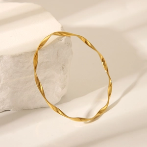 Elegant gold Mobius twist bangle in stainless steel displayed on a stone with soft shadows