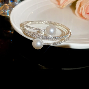 Close-up of a multi-layer silver pearl bracelet with pave-set zircon on white ceramic