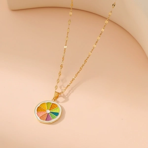 Golden necklace with a colorful enamel lemon slice pendant on a beige minimalist background