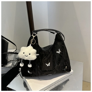 Detail of black pleated bag with silver butterfly charm and white cloud pendant