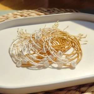 Macro shot of gold beads and letter beads on white ceramic tray with soft lighting