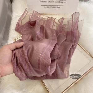 Close-up of pink silk wool scarf showing semi-transparent texture and golden stripes