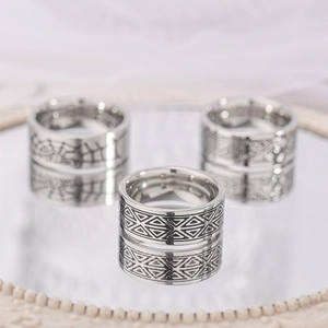 Dettaglio macro di anelli in titanio argento con ragnatela e incisioni geometriche