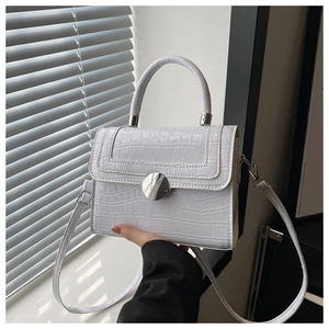 Detail of white crocodile embossed mini square bag with round silver metal buckle clasp