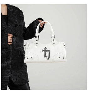 Detail der weißen Punk-Motorradtasche mit Metallkreuz und Kettenriemen auf schwarzem Blazer