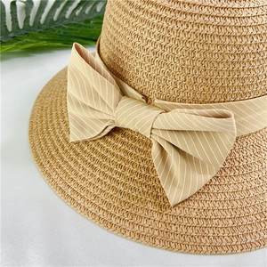 Detail of hand-woven straw hat with elegant striped bow on minimalist white background