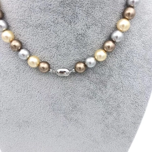 Macro shot of multi-colored pearls in gold, silver and brown with a silver metal clasp