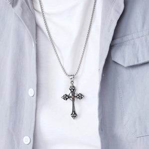 Close-up of retro titanium steel cross pendant with red gem worn on a box chain
