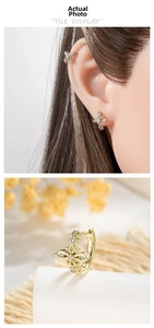Detail of gold hollow cross earring with white zircons on ear model and display stand