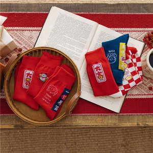 Festive red and blue socks with lucky embroidery and patterns on a bamboo tray