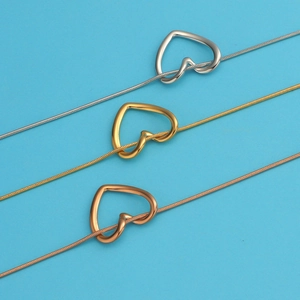 Close-up of heart-shaped pendant necklaces in silver, gold, and rose gold finishes