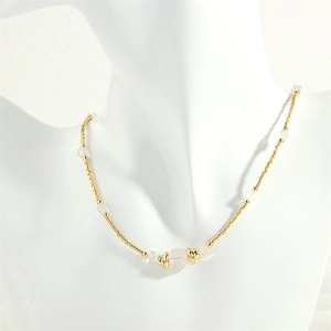 Detail of beaded gold chain necklace with white translucent stones on a white mannequin